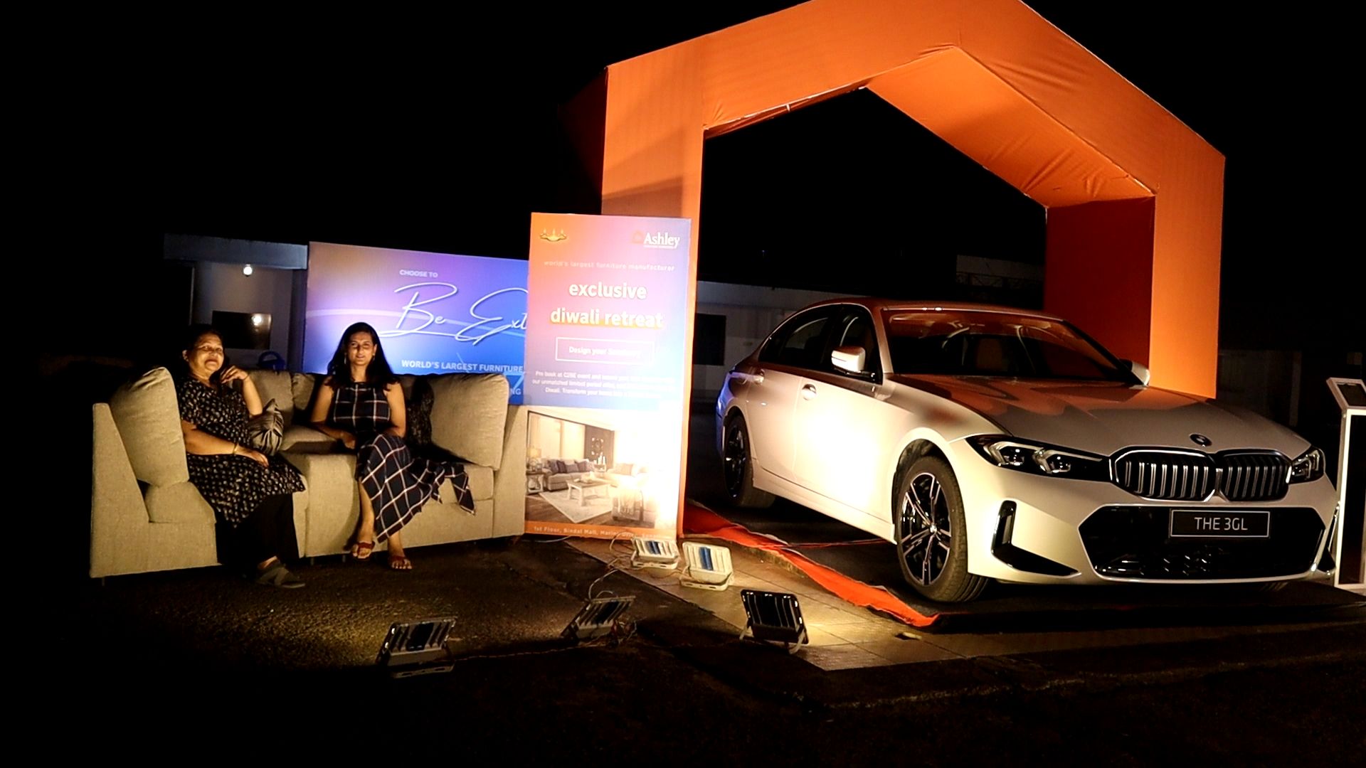 Car under event lighting beside a staged setup